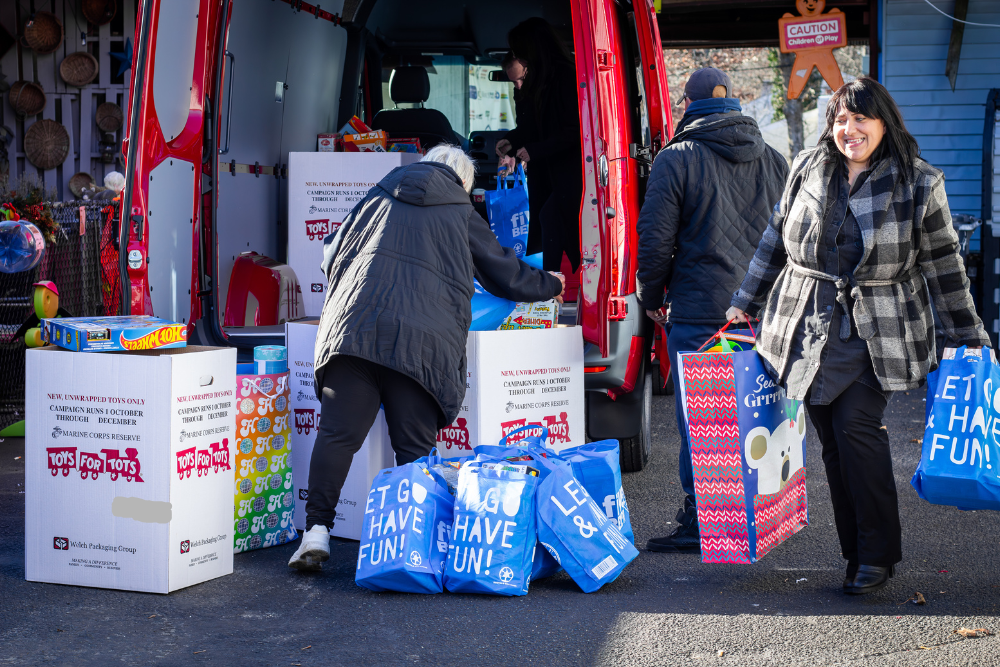 People loading bags of toys into a red van for the Marine Corps Reserve's 'Toys for Tots' campaign.
