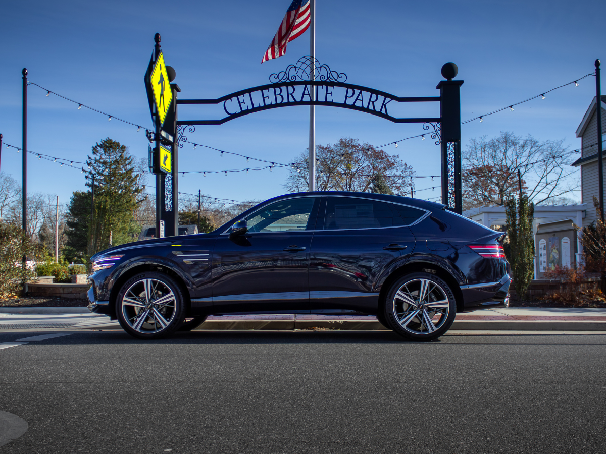 Dark blue SUV parked on a street with a 'Celebrate Park' arch and American flag in the background.