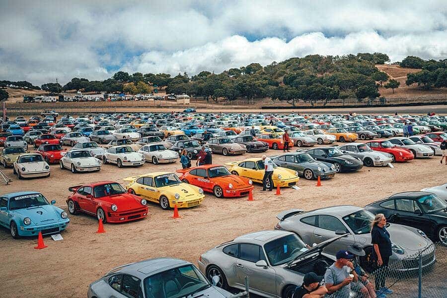lots of people are around classic Porsche cars of various colors
